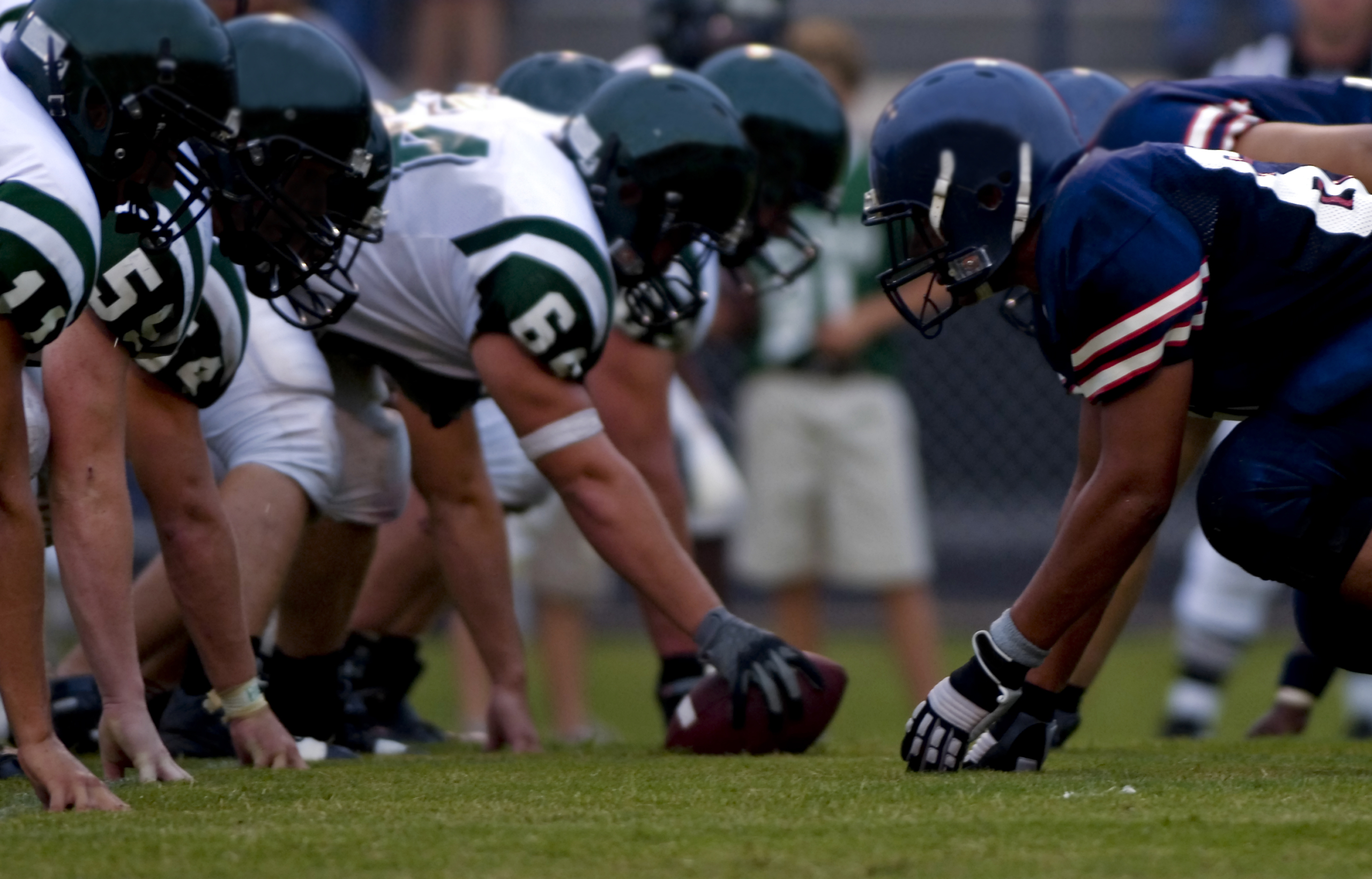 Football players lined up at the line of scrimmage, illustrating the neuroscience of athlete mental health, focus under pressure, and nervous system regulation.