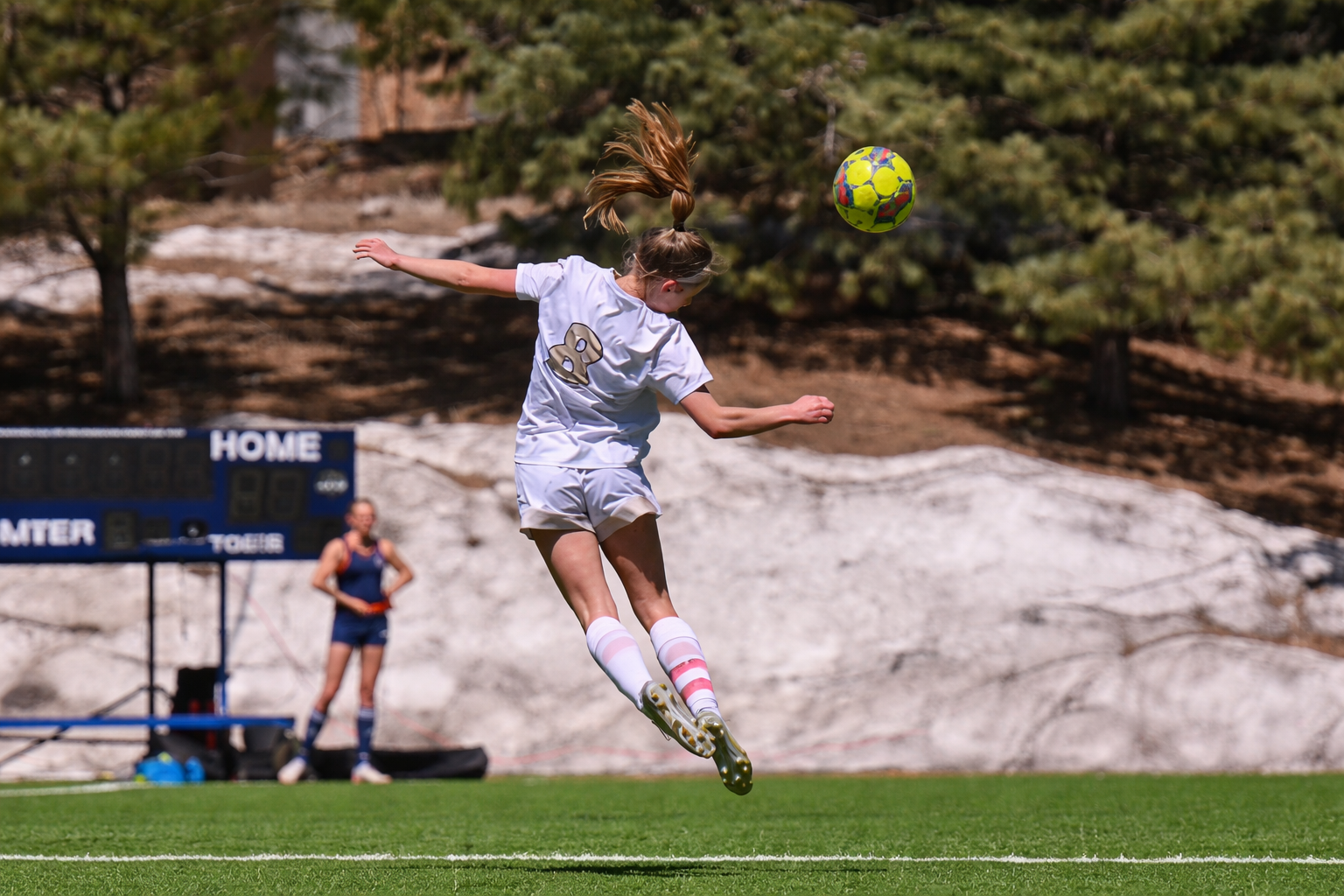 Young soccer athlete jumping to head the ball during a match, representing the challenge of returning to sport after injury and overcoming fear of reinjury